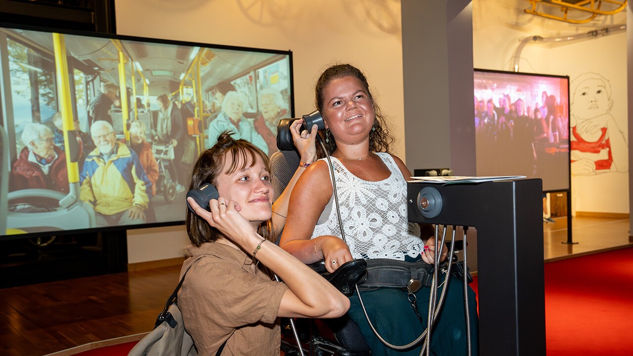 Eine Person im Rollstuhl gemeinsam mit ihrer Assistentin im Museum